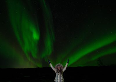 Guest beneath vibrant Northern Lights in Iceland