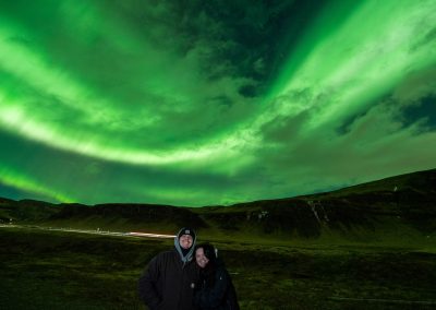 Visitors standing beneath swirling Northern Lights