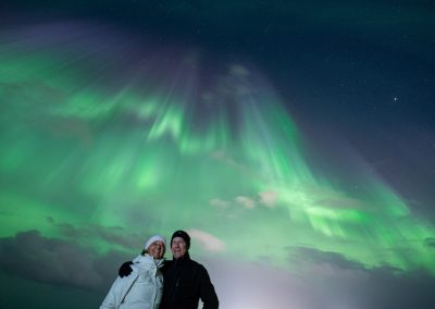 Couple beneath purple and green Northern Lights